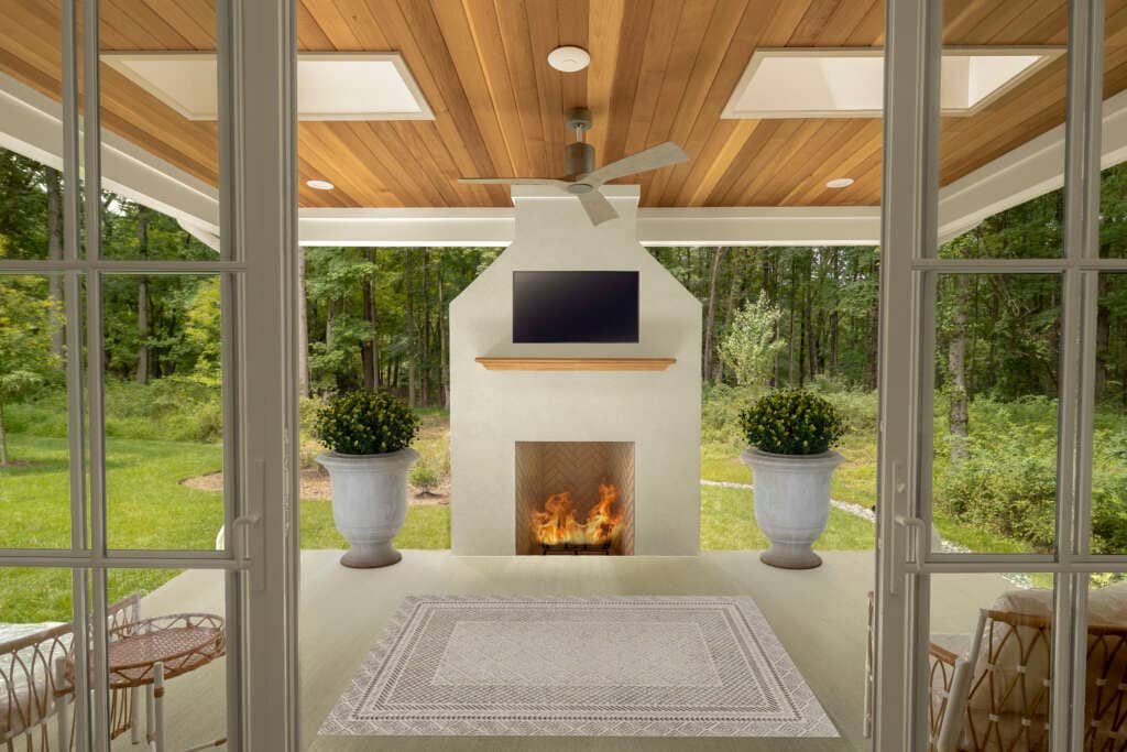 outdoor covered back porch with outdoor fireplace, greenery, and sitting area 